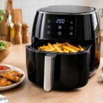 Appareil à airfryer noir cuisant frites et poulet sur plan de travail