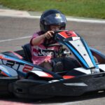 Un enfant en karting sur circuit, portant casque, pilotant go-kart rouge