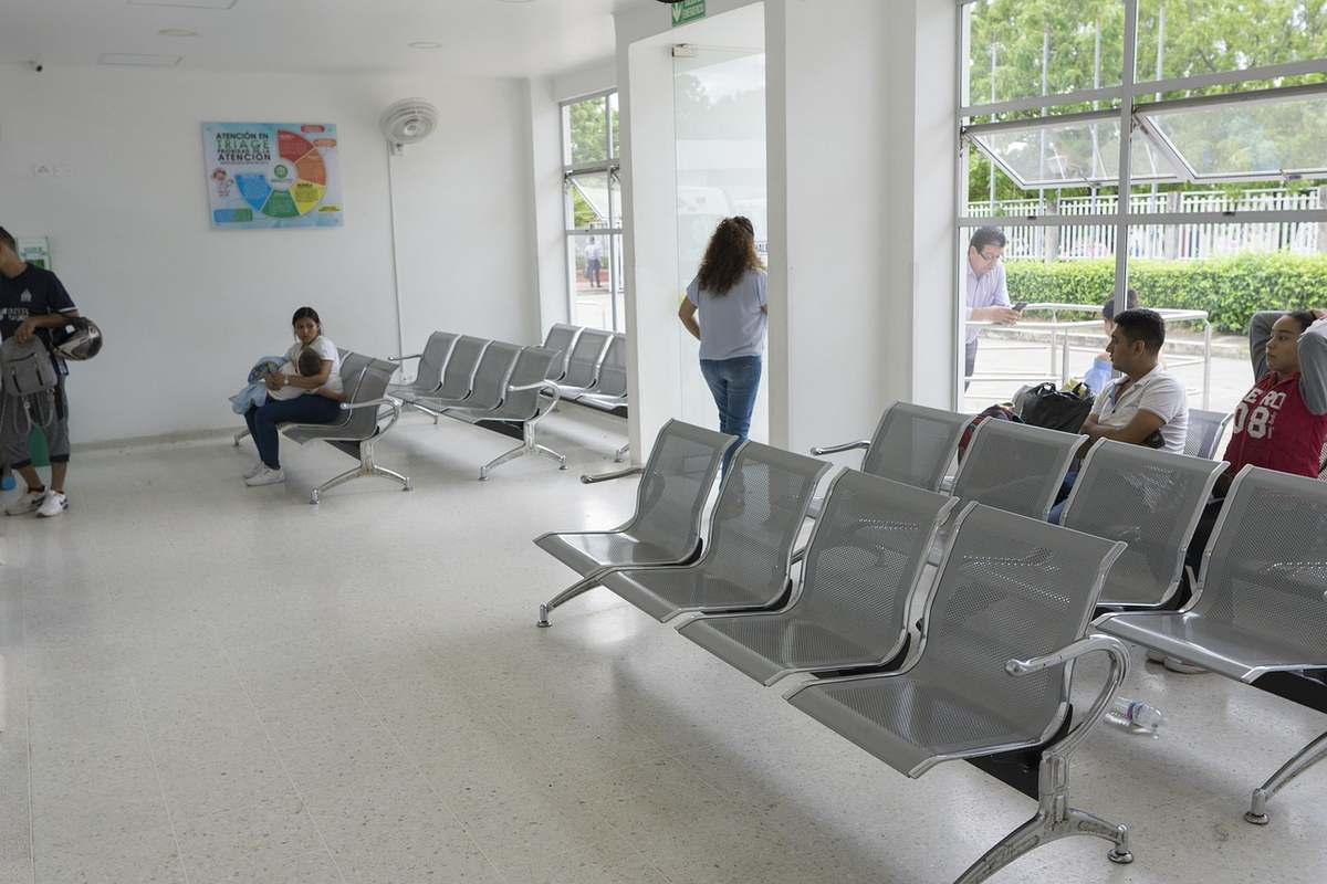 Salle d'attente avec chaises métalliques et personnes en attente Salle d'attente avec chaises métalliques et personnes en attente